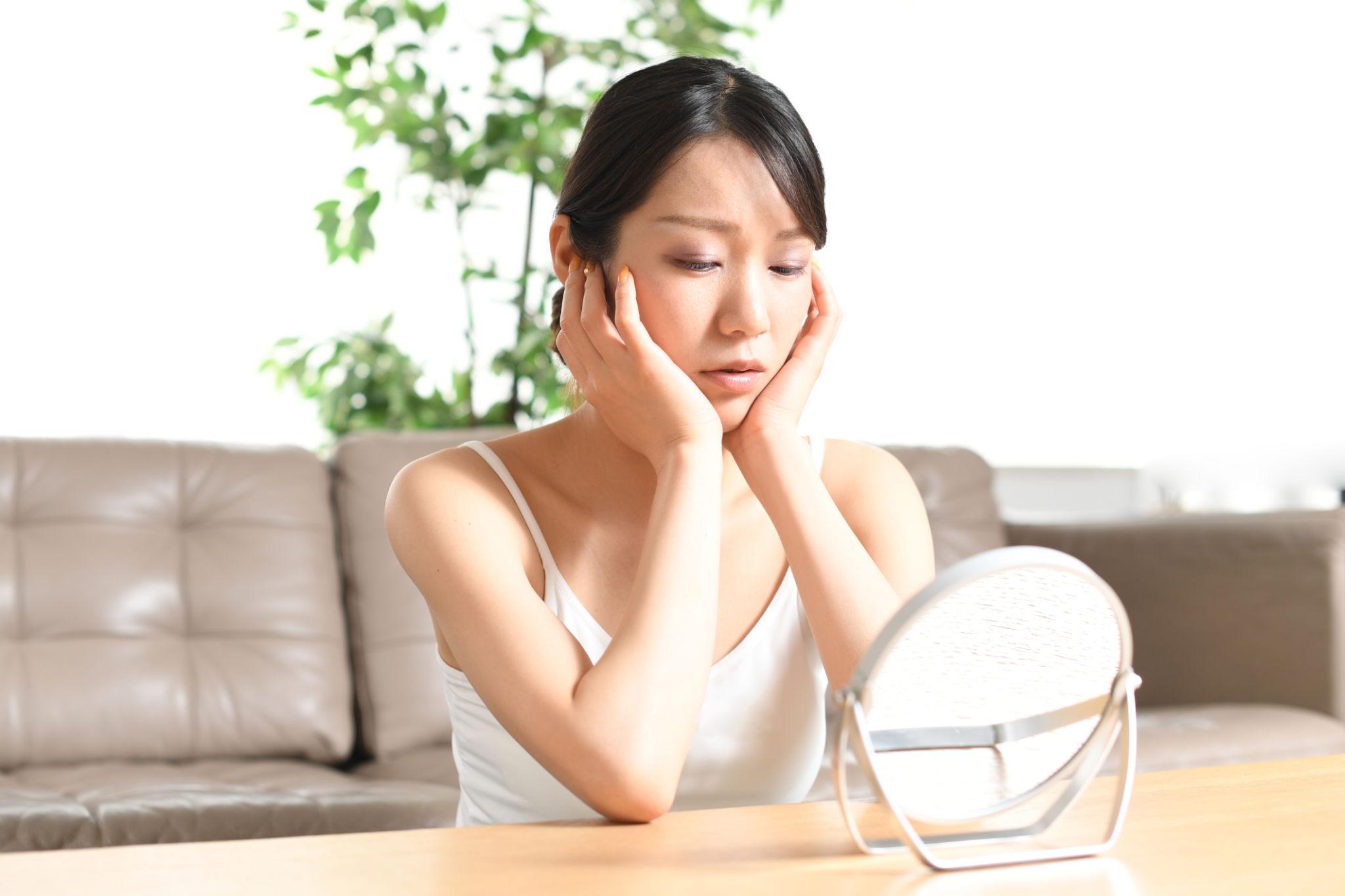 鏡を見て悩む女性